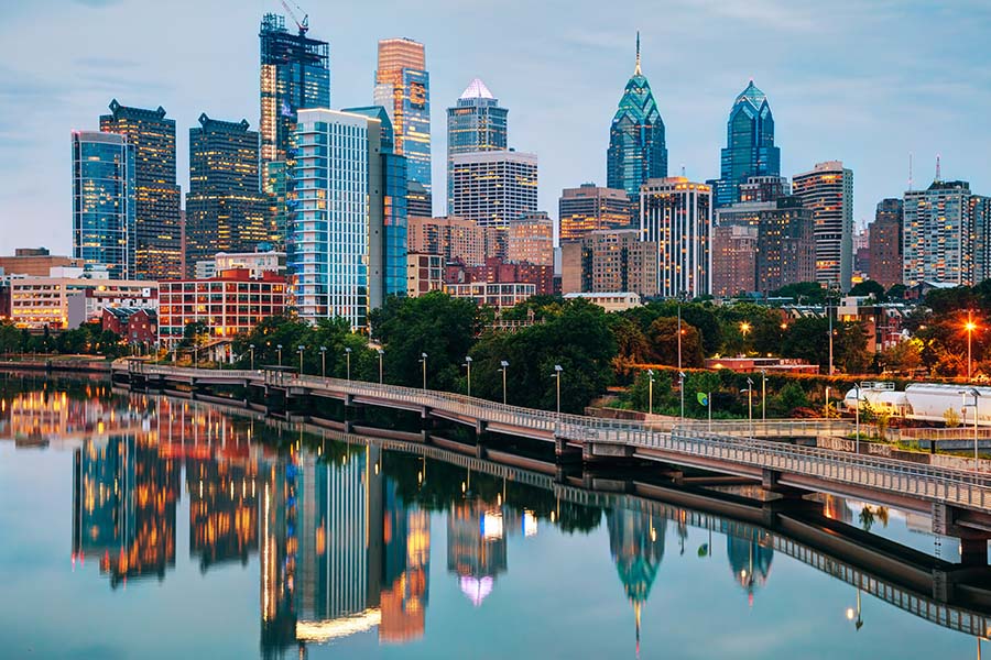 Contact - Long Distance View of Philadelphia Skyline During the Evening Displaying Many Tall Buildings and a River